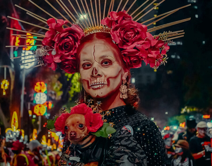 Floral headpieces, ornate costumes, and detailed face paint are central to the Día de los Muertos parades