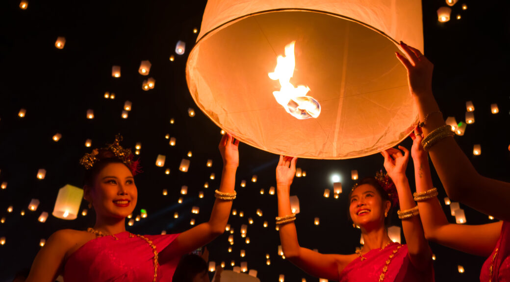 Dancers in traditional Thai attire release lanterns during the Yi Peng festival