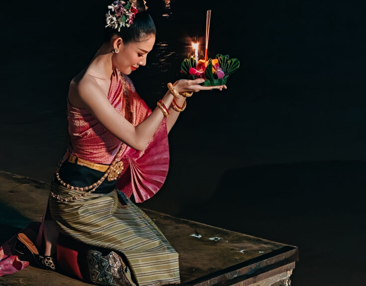 A Loy Krathong participant holds a decorated krathong before setting it on the river
